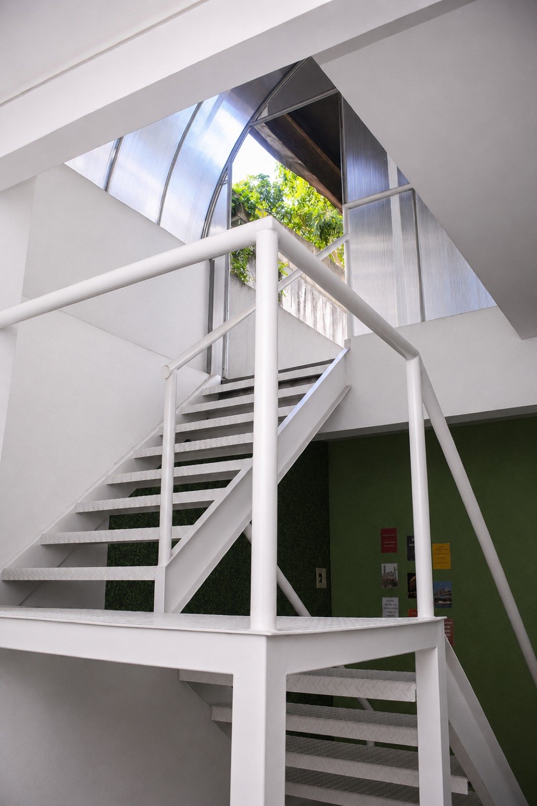 Escada branca sob a claraboia na área comum do Cunhatã Hostel