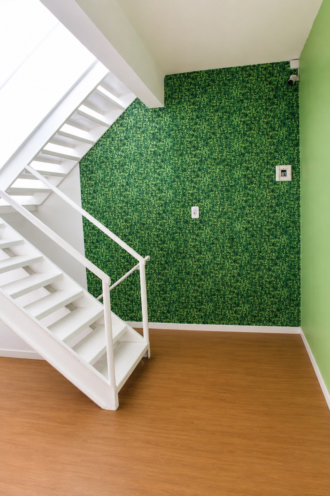 Escada branca ao lado da parede de jardim vertical na área comum do Cunhatã Hostel, em Belém