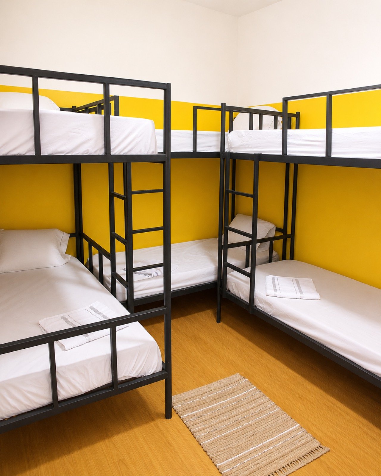 Quarto compartilhado de seis camas do Cunhatã Hostel com três beliches e parede amarela