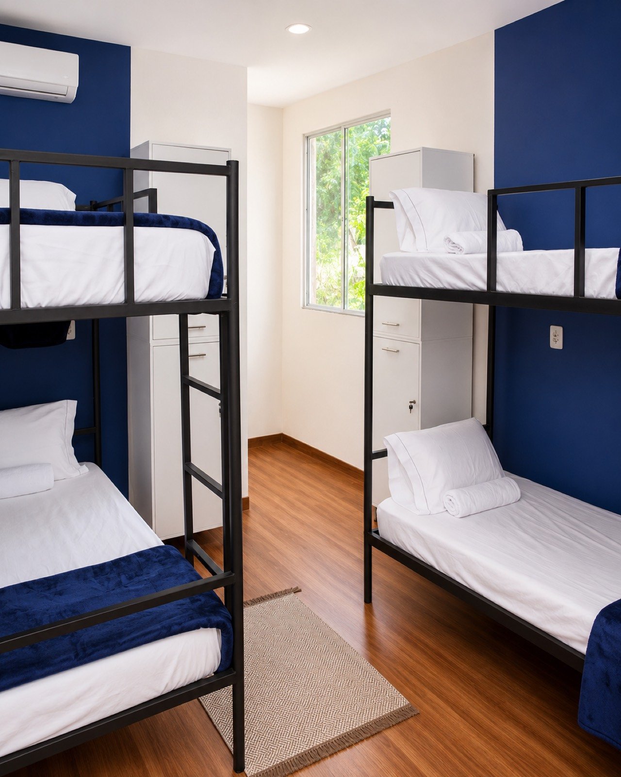 Quarto compartilhado de quatro camas do Cunhatã Hostel com beliches e parede azul