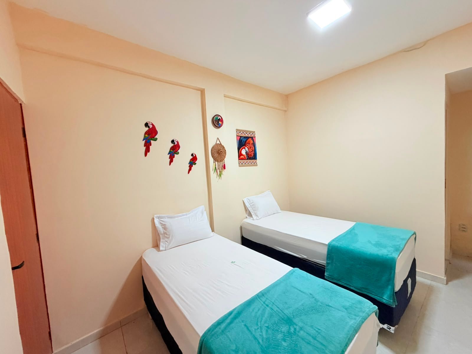 Quarto privativo twin do Cunhatã Hostel com duas camas de solteiro e araras de madeira na parede