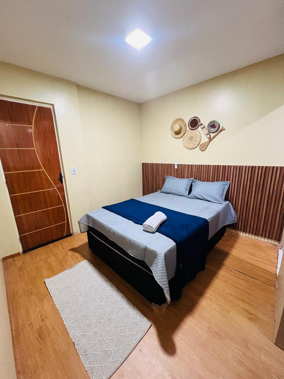 Suíte privativa de casal do Cunhatã Hostel com cabeceira ripada de madeira, pronta para receber hóspedes