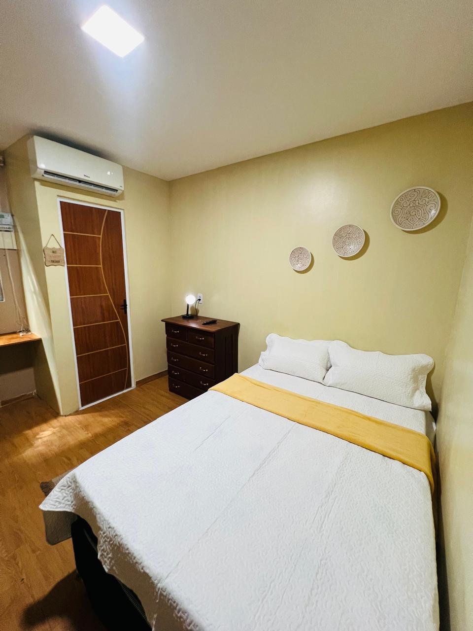 Suíte privativa de casal do Cunhatã Hostel com cômoda e pratos marajoara na parede
